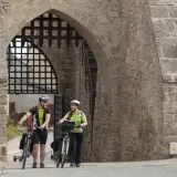 Para rowerzystów w kaskach pod kamiennym łukiem, gotowi na chańcza zalew trasę.