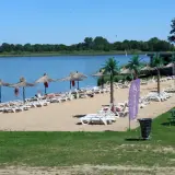 Słoneczny dzień nad jeziorem koło Wrocławia. Piasek, leżaki, parasole i palmy tworzą wakacyjny klimat.