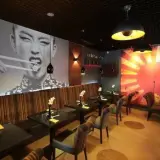 Wnętrze azjatyckiej restauracji w Szczecinie, z wielkoformatowym zdjęciem kobiety jedzącej pałeczkami. Idealne miejsce na romantyczną kolację, jeśli szukasz najlepszych restauracje szczecin ranking.