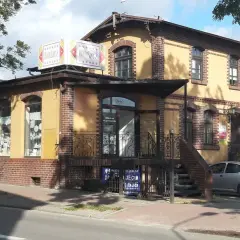Bar "Barszcz" w Wejherowie. Żółty budynek z ceglanymi zdobieniami, szyldem "Barszcz" i małym srebrnym samochodem.