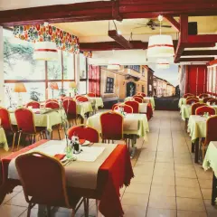Wnętrze restauracji z czerwonymi krzesłami i zielonymi obrusami, jak na balu czardasz w Gdańsku.