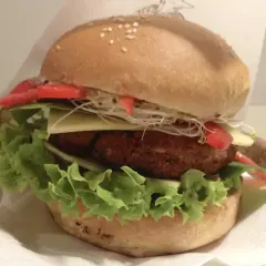Pyszny burger z Krowarzywa Kraków: soczysty kotlet roślinny, świeża sałata, ser, pomidor i kiełki w miękkiej bułce.