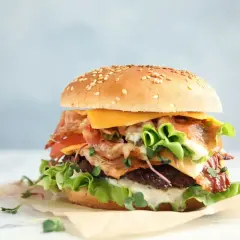 Pyszny whooper z chrupiącym boczkiem, serem i świeżymi warzywami na sezamowej bułce.
