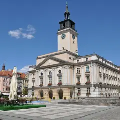 Rynek w Kaliszu, najstarszym mieście w Polsce, z ratuszem i kawiarnianymi stolikami.