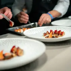 Szefowie kuchni w atelier Amaro precyzyjnie układają dania na talerzach.