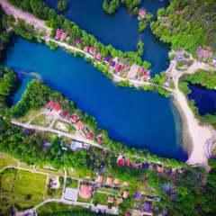 Malownicze rokitki jezioro otoczone lasem i domkami z czerwonymi dachami. Woda lśni błękitem, a plaża zaprasza do odpoczynku.