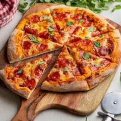 Pyszna pizza z peperoni, ciągnącym serem i świeżą bazylią, pokrojona na kawałki na drewnianej desce.