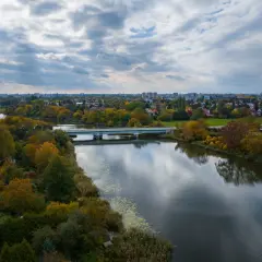 Jesioro Czerniakowskie w jesiennej szacie, z mostem i panoramą miasta w tle.