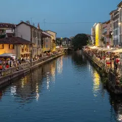 Wieczór nad kanałami Navigli w Mediolanie. Tłumy ludzi spacerują wzdłuż wody, siedzą w kawiarniach i restauracjach.