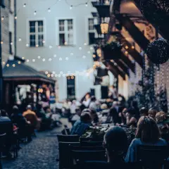 Wieczorny ogródek restauracyjny we Wrocławiu, pełen ludzi. Idealne miejsce na kolację, które z pewnością znajdzie się w rankingu restauracji Wrocław.