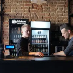 Pracownicy w Bobby Burger Bydgoszcz za ladą, obok lodówki z napojami i ekspresu do kawy.