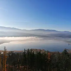 Mglisty poranek nad zbiornikiem Sosnówka. W oddali góry, a na pierwszym planie jesienny las.