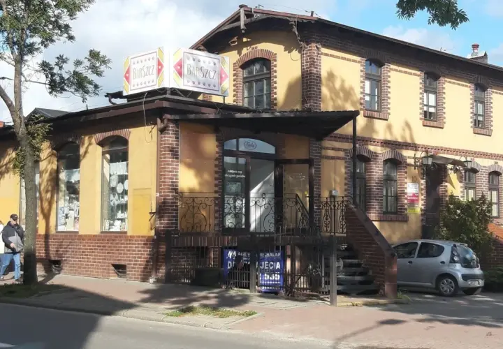 Bar "Barszcz" w Wejherowie. Żółty budynek z ceglanymi zdobieniami, szyldem "Barszcz" i małym srebrnym samochodem.