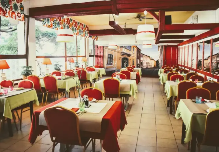 Wnętrze restauracji z czerwonymi krzesłami i zielonymi obrusami, jak na balu czardasz w Gdańsku.