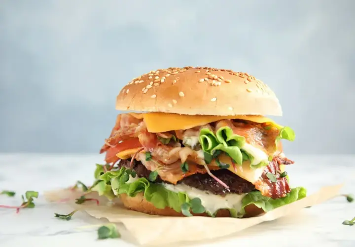 Pyszny whooper z chrupiącym boczkiem, serem i świeżymi warzywami na sezamowej bułce.