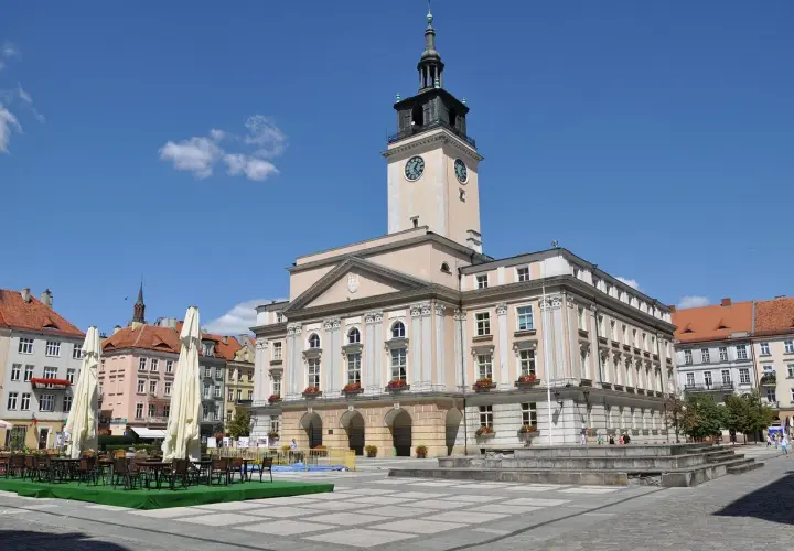 Rynek w Kaliszu, najstarszym mieście w Polsce, z ratuszem i kawiarnianymi stolikami.