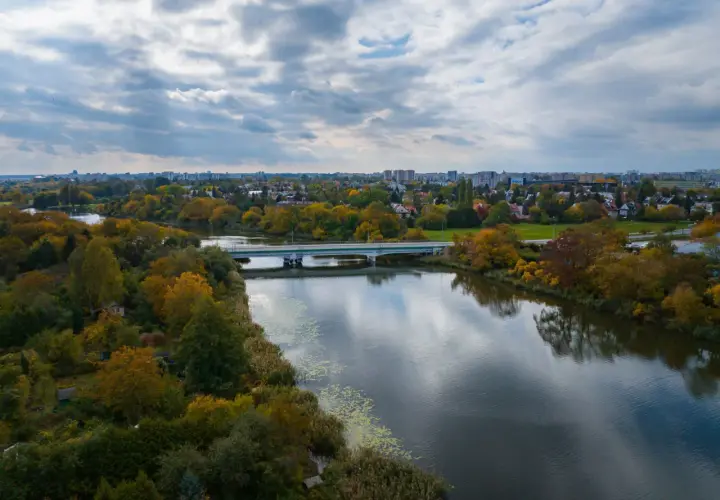 Jesioro Czerniakowskie w jesiennej szacie, z mostem i panoramą miasta w tle.
