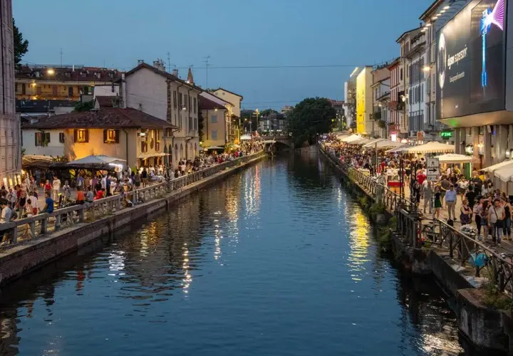 Wieczór nad kanałami Navigli w Mediolanie. Tłumy ludzi spacerują wzdłuż wody, siedzą w kawiarniach i restauracjach.