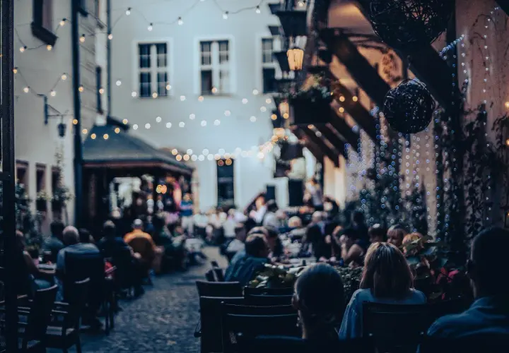 Wieczorny ogródek restauracyjny we Wrocławiu, pełen ludzi. Idealne miejsce na kolację, które z pewnością znajdzie się w rankingu restauracji Wrocław.