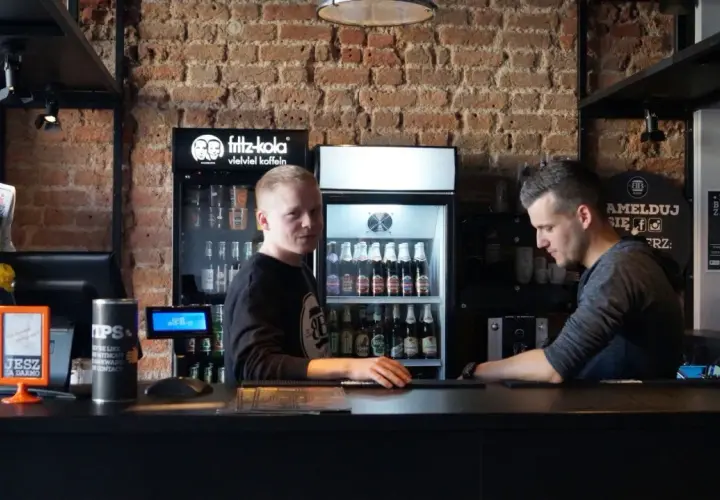 Pracownicy w Bobby Burger Bydgoszcz za ladą, obok lodówki z napojami i ekspresu do kawy.