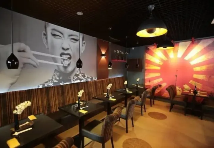 Wnętrze azjatyckiej restauracji w Szczecinie, z wielkoformatowym zdjęciem kobiety jedzącej pałeczkami. Idealne miejsce na romantyczną kolację, jeśli szukasz najlepszych restauracje szczecin ranking.