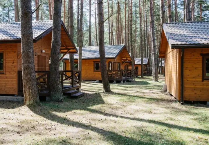 Drewniane domki letniskowe w lesie, idealne na wypoczynek nad jeziorem. Roś.