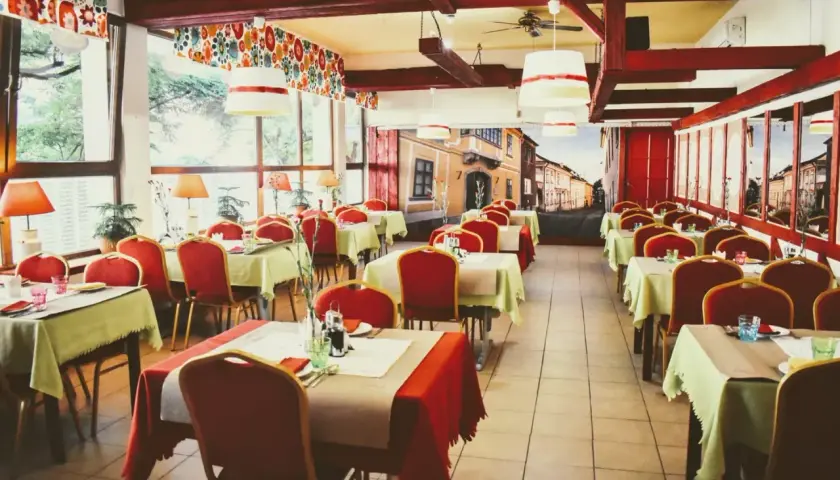 Wnętrze restauracji z czerwonymi krzesłami i zielonymi obrusami, jak na balu czardasz w Gdańsku.