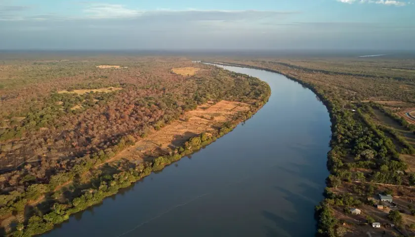 Szeroka rzeka Niger meandruje przez sawannę, otoczona bujną roślinnością i nielicznymi osadami.