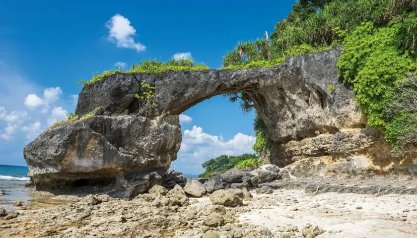 Skalny łuk na plaży, jakby stworzony przez naturę na Andamanach. Słońce, morze i bujna roślinność.