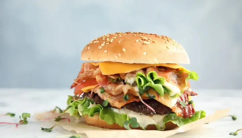 Pyszny whooper z chrupiącym boczkiem, serem i świeżymi warzywami na sezamowej bułce.