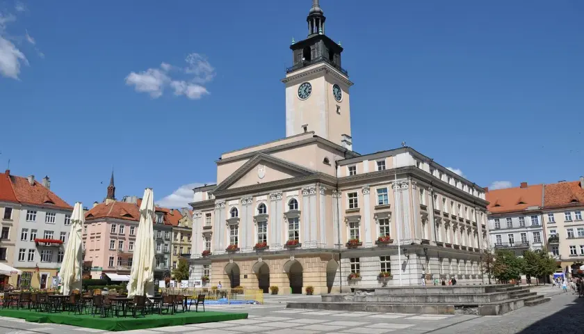 Rynek w Kaliszu, najstarszym mieście w Polsce, z ratuszem i kawiarnianymi stolikami.