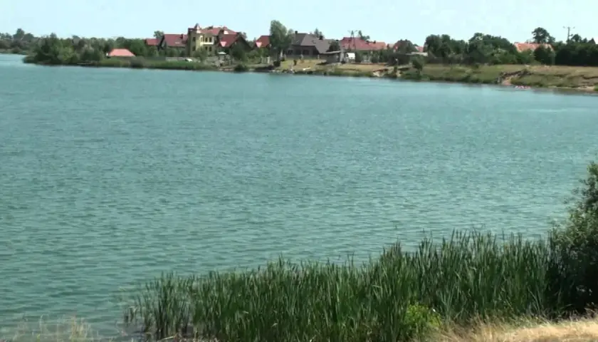 Spalona jezioro z domami na brzegu i trzcinami.