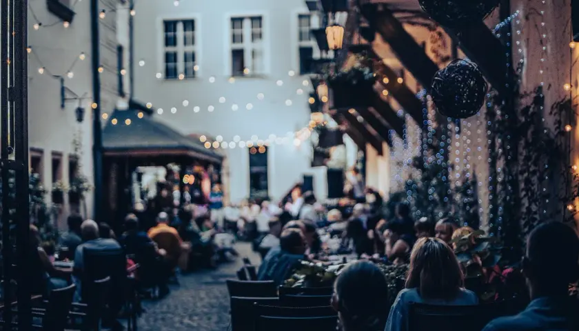 Wieczorny ogródek restauracyjny we Wrocławiu, pełen ludzi. Idealne miejsce na kolację, które z pewnością znajdzie się w rankingu restauracji Wrocław.