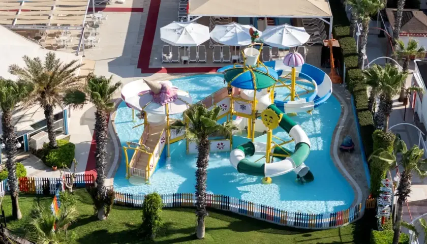 Kolorowy aquapark w Orange County Belek, z palmami i zjeżdżalniami, zaprasza do zabawy.
