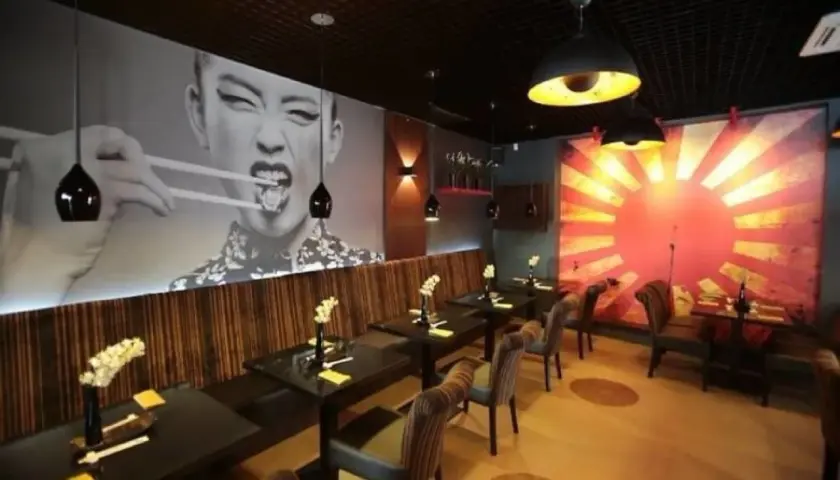 Wnętrze azjatyckiej restauracji w Szczecinie, z wielkoformatowym zdjęciem kobiety jedzącej pałeczkami. Idealne miejsce na romantyczną kolację, jeśli szukasz najlepszych restauracje szczecin ranking.