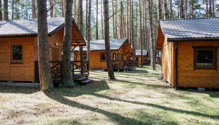Drewniane domki letniskowe w lesie, idealne na wypoczynek nad jeziorem. Roś.