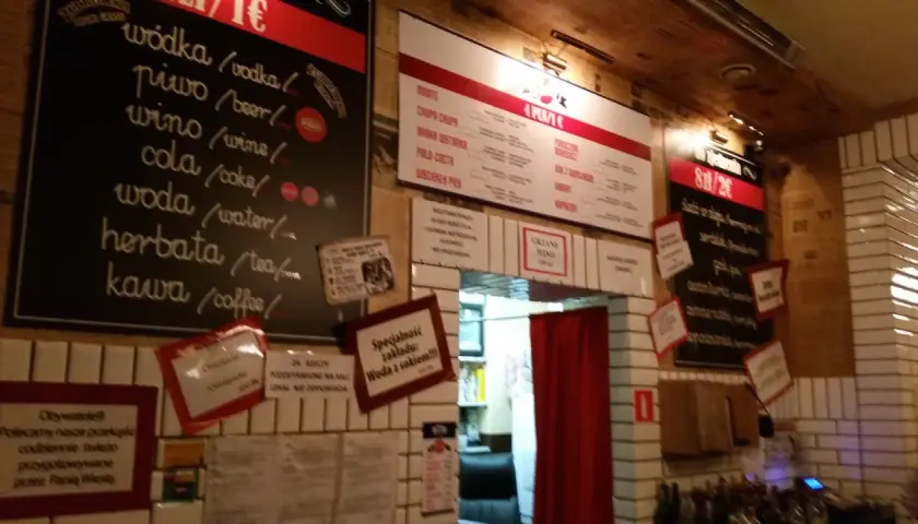 Wnętrze pijalni wódki i piwa. Menu z napojami i przekąskami na tablicach.