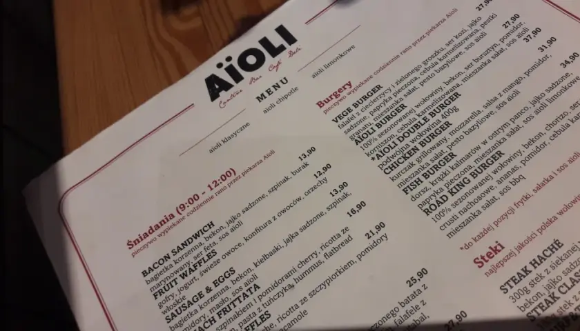 Menu Aïoli z opisami dań, w tym burgerów i śniadań.