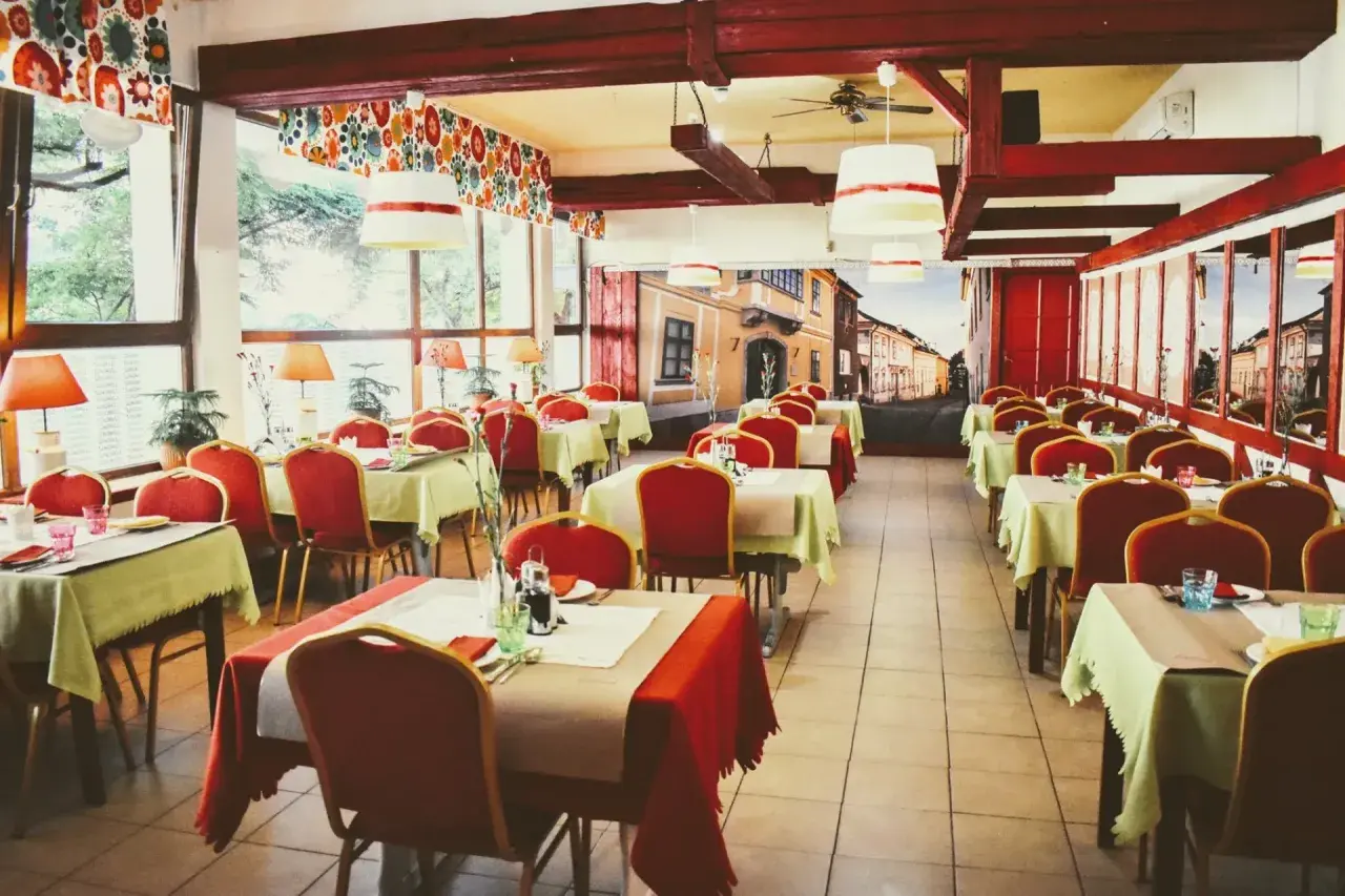 Wnętrze restauracji z czerwonymi krzesłami i zielonymi obrusami, jak na balu czardasz w Gdańsku.