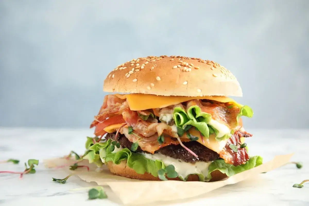 Pyszny whooper z chrupiącym boczkiem, serem i świeżymi warzywami na sezamowej bułce.