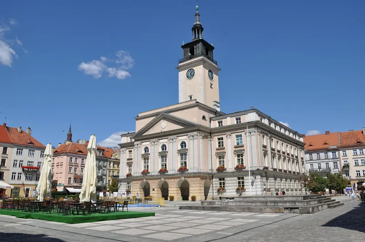 Rynek w Kaliszu, najstarszym mieście w Polsce, z ratuszem i kawiarnianymi stolikami.