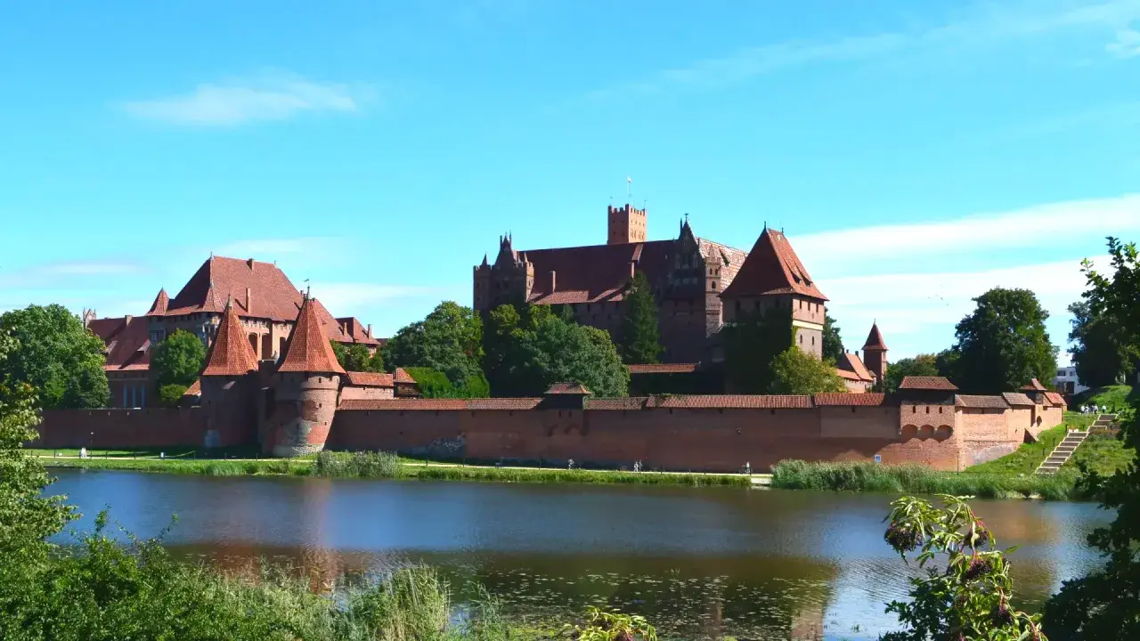 Potężny zamek w Malborku nad jeziorem. Zwiedzanie zamku w Malborku to podróż w czasie, warto zaplanować cały dzień.