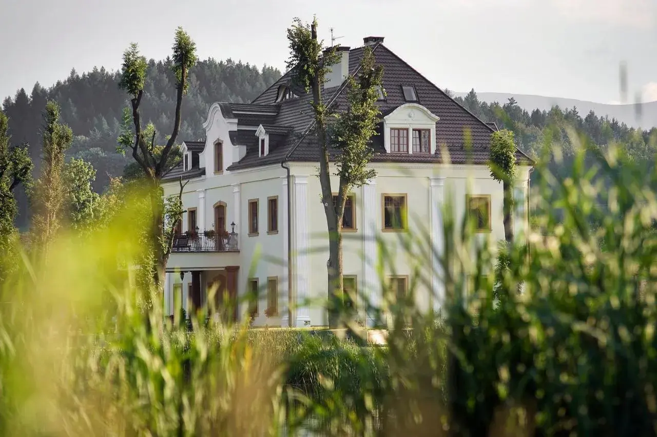 Elegancka restauracja kaczka na wodzie, otoczona zielenią, z widokiem na las i góry.