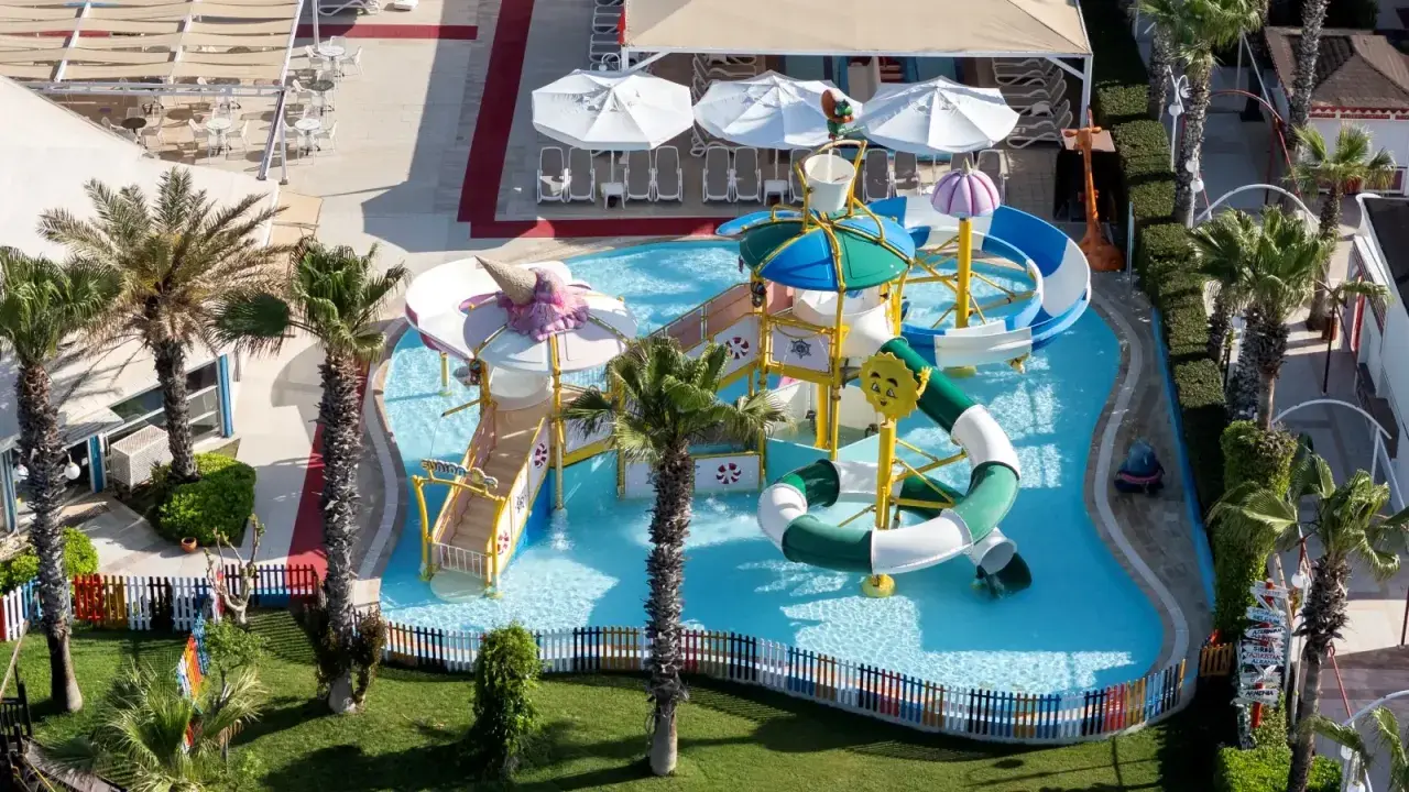 Kolorowy aquapark w Orange County Belek, z palmami i zjeżdżalniami, zaprasza do zabawy.