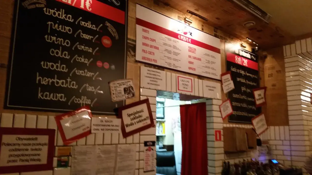 Wnętrze pijalni wódki i piwa. Menu z napojami i przekąskami na tablicach.
