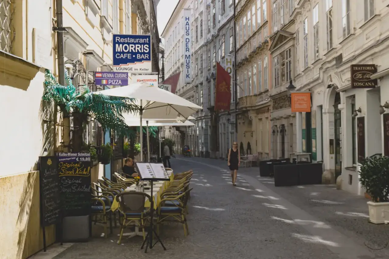 Ulica w Wiedniu Erdberg z restauracją Morris i menu Wiener Schnitzel. Kobieta spaceruje po chodniku.