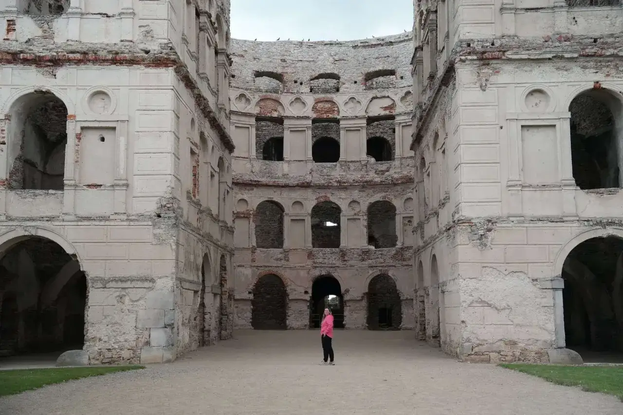 Ruiny zamku Krzyżtopór. Zwiedzający z różowym swetrem podziwia architekturę. Bilety do Krzyżtoporu warto kupić online.