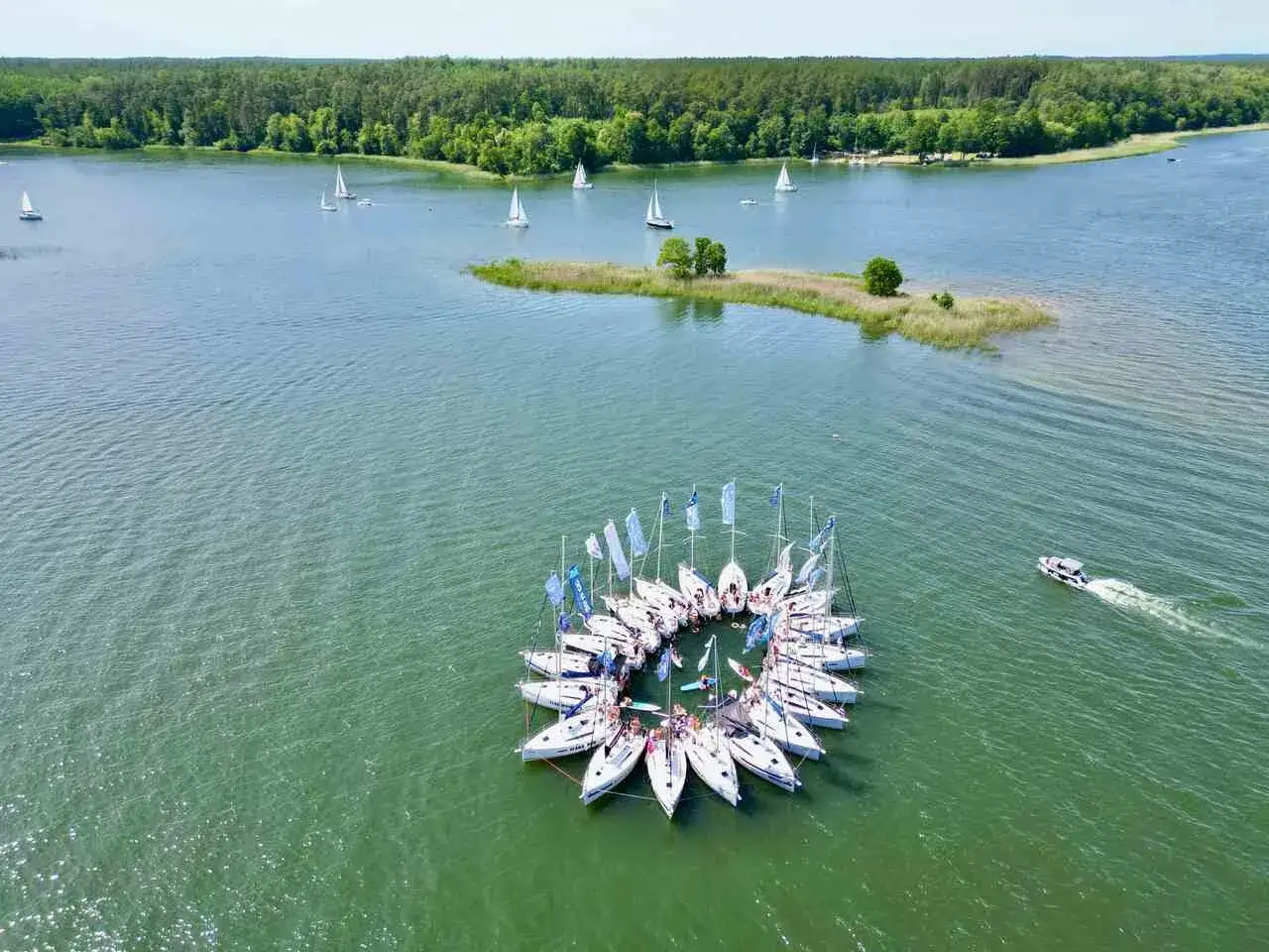 Żeglarska feta na Mazurach! Jachty tworzą okrąg, a w tle las i jezioro. Idealne miejsce, by zapytać: gdzie na Mazury?