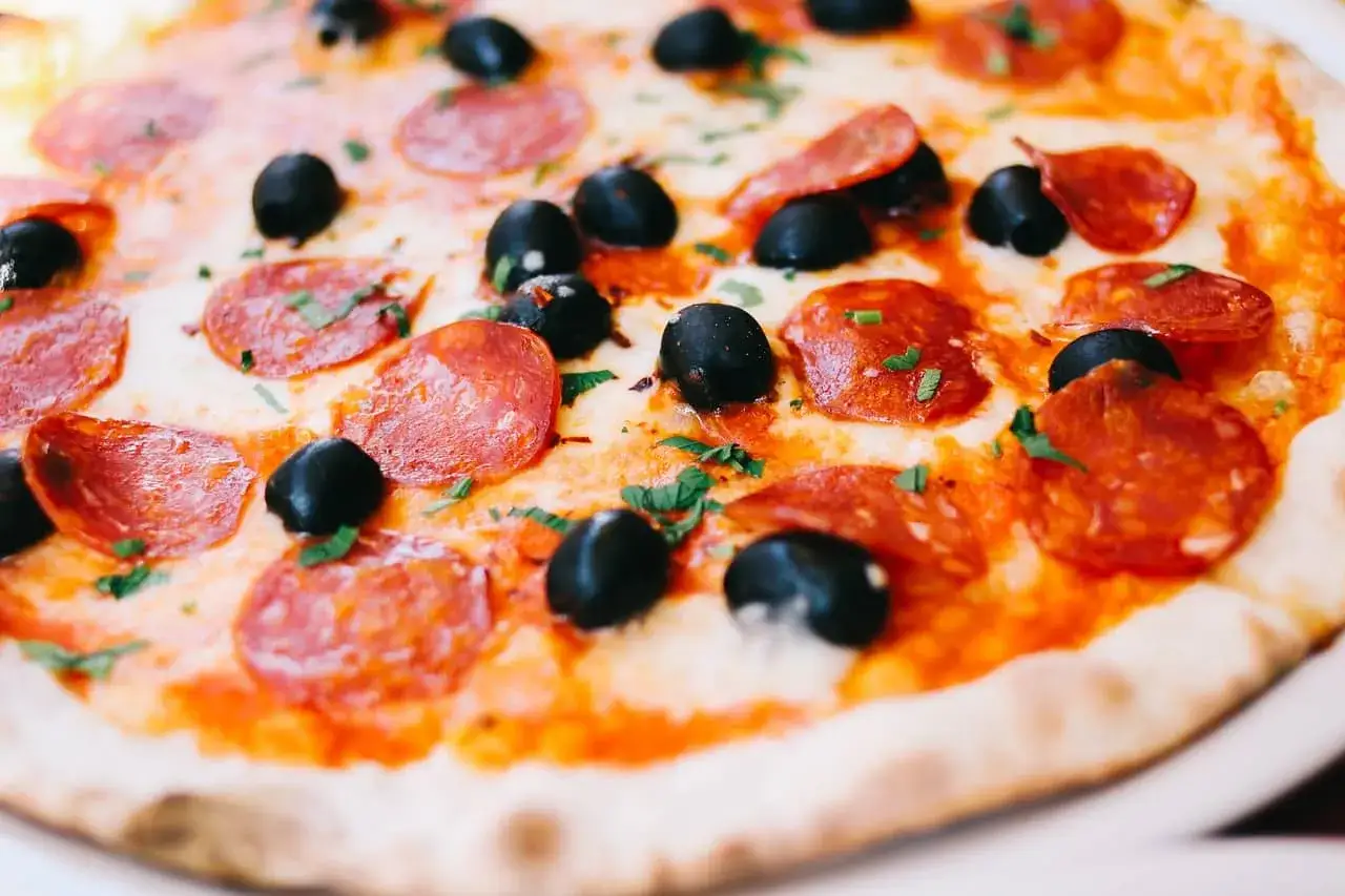 Apetyczna pizza z chrupiącym ciastem, ciągnącym serem, czarnymi oliwkami i pikantnym peperoni.