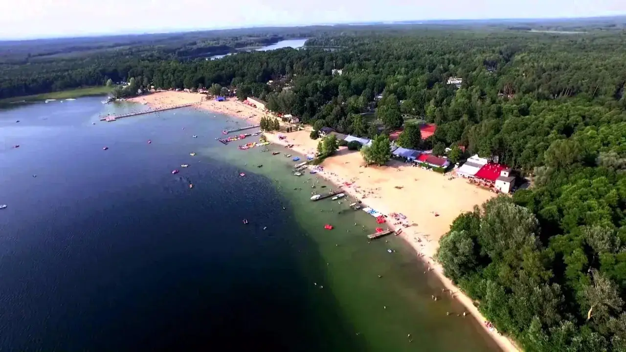 Skorzęcin jezioro tętni życiem. Tłumy plażowiczów, łódki i kąpieliska tworzą wakacyjny obraz.